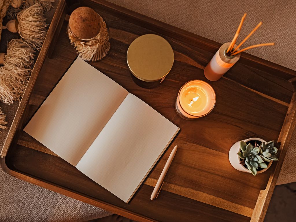 A weekly planner sitting on a tray with calming accessories like incense and candles to discover calm planning